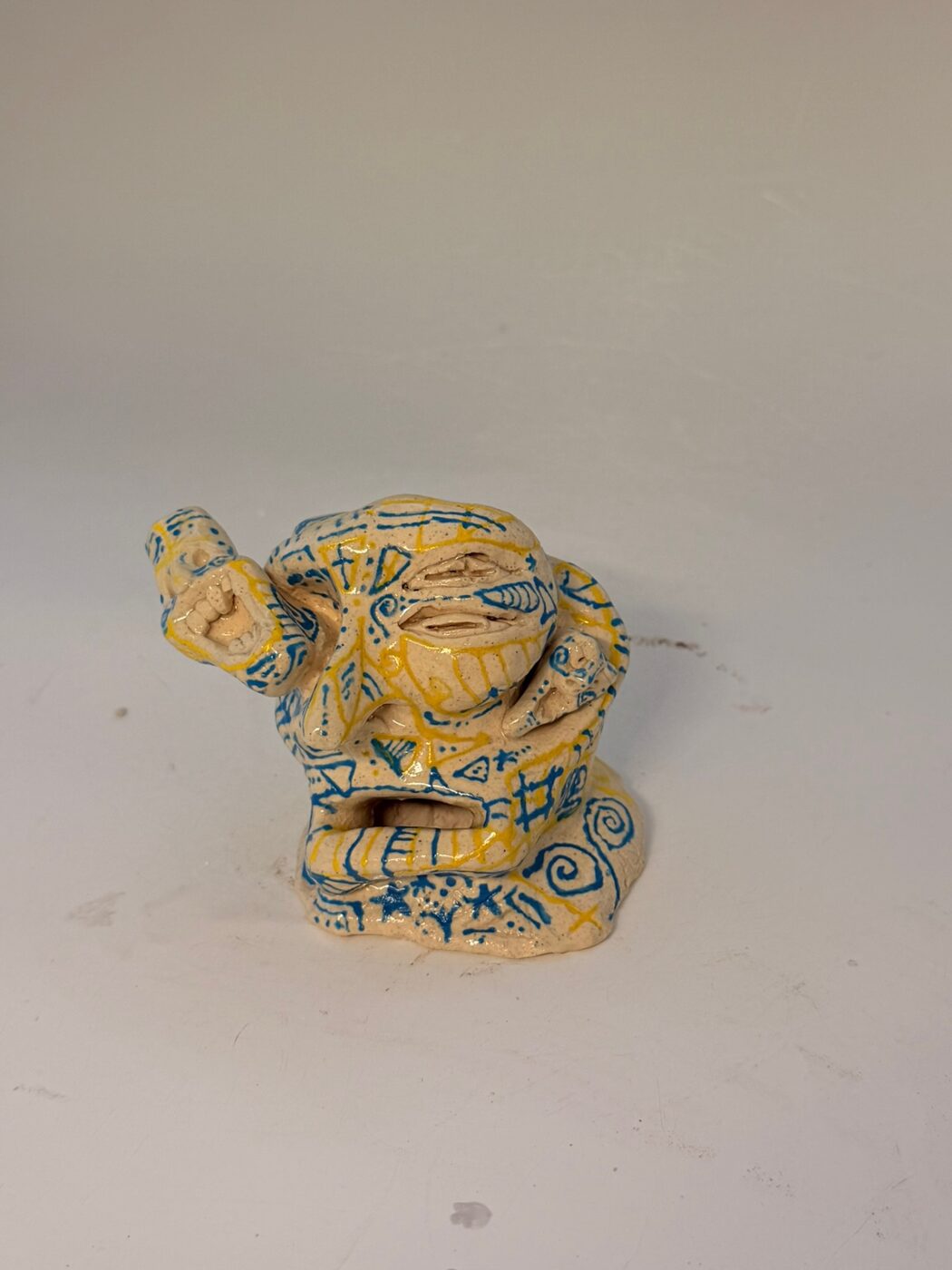 Finished Double-Face Sculpture glazed in cream with blue and yellow carved line work