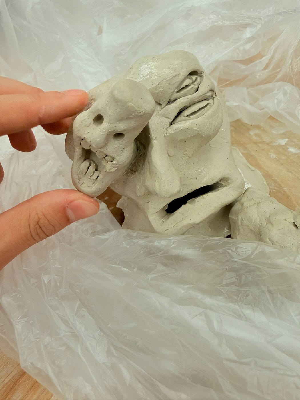 Double-Face Sculpture in unfired gray clay showing two sculpted faces