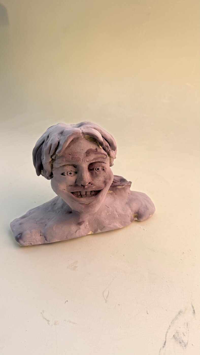 Hand-built figural bust in lavender colored clay with a sculpted smiling face